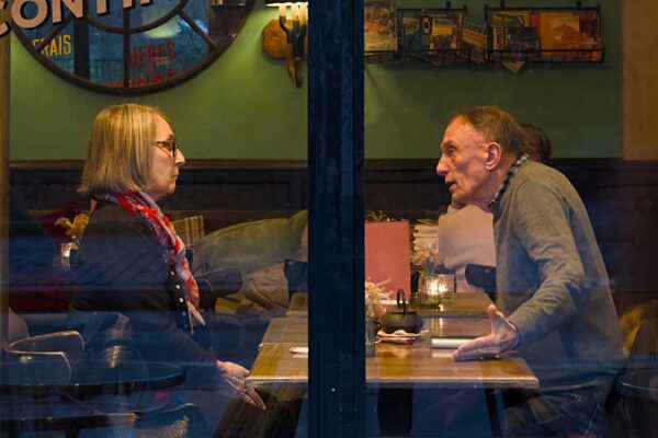 Two people talking at a table inside a cafe