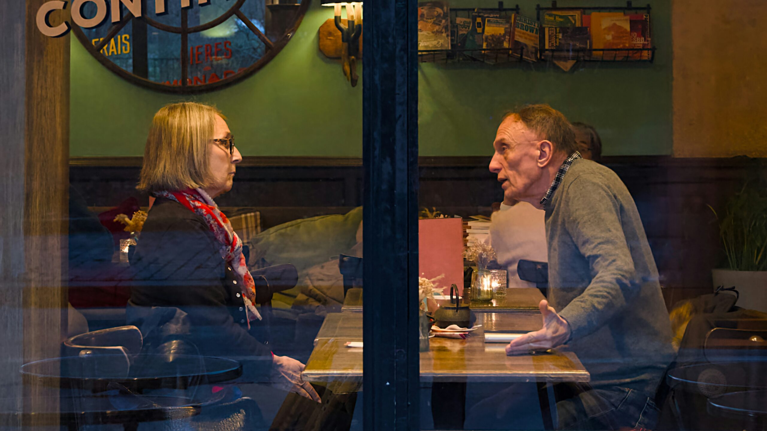 Two people talking at a table inside a cafe