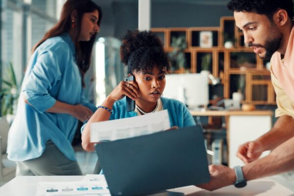 Business woman phone call and overwhelmed in office with paperwork laptop and proposal in agency Chaos deadline and tech with multitasking stress and burnout with documents and busy staff