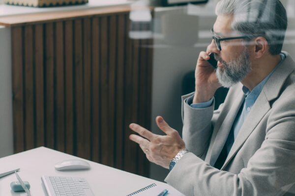 A man sitting at a desk talking on a cell phone