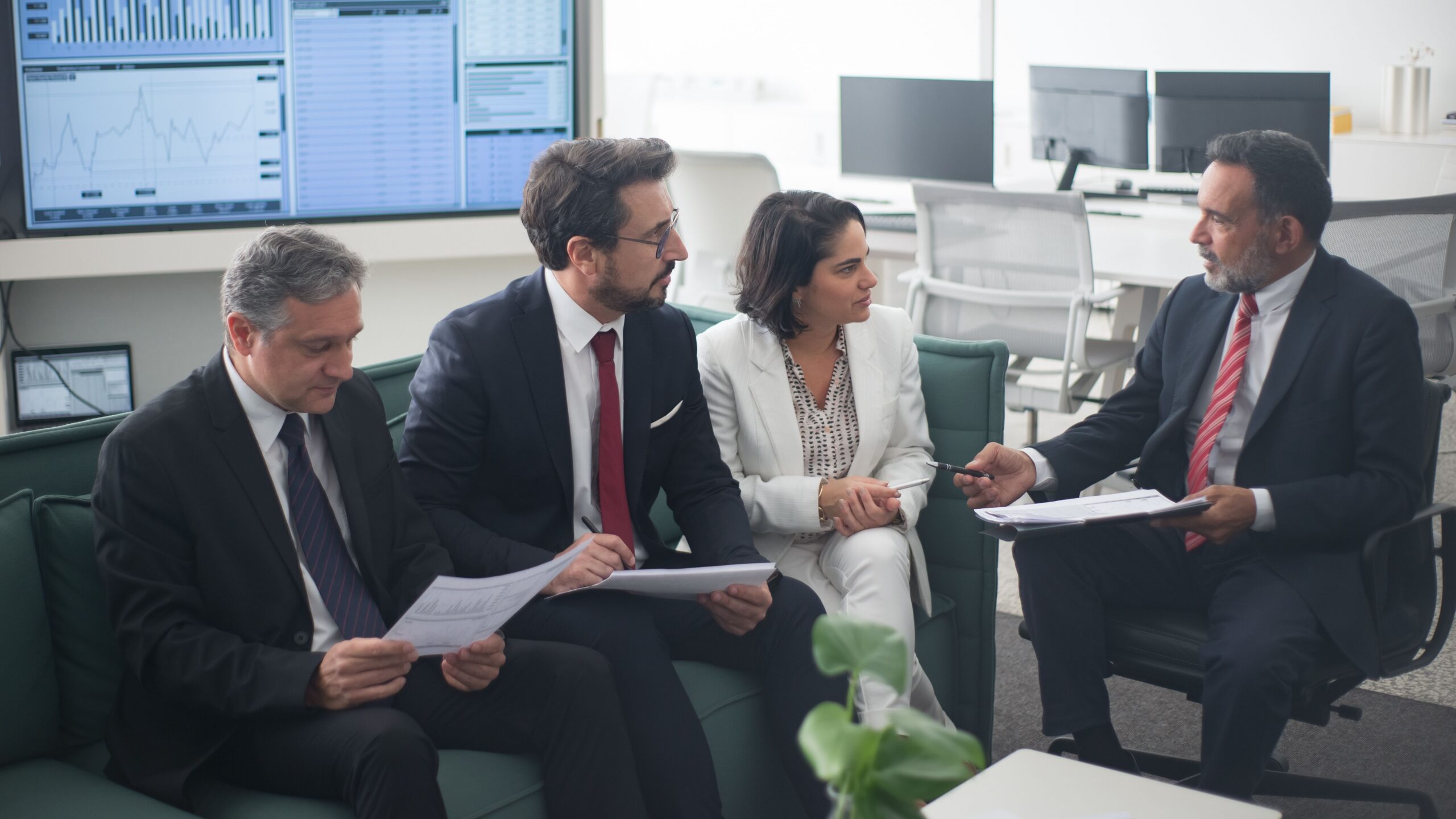 Group of business professionals discussing financial strategies in a modern office setting.