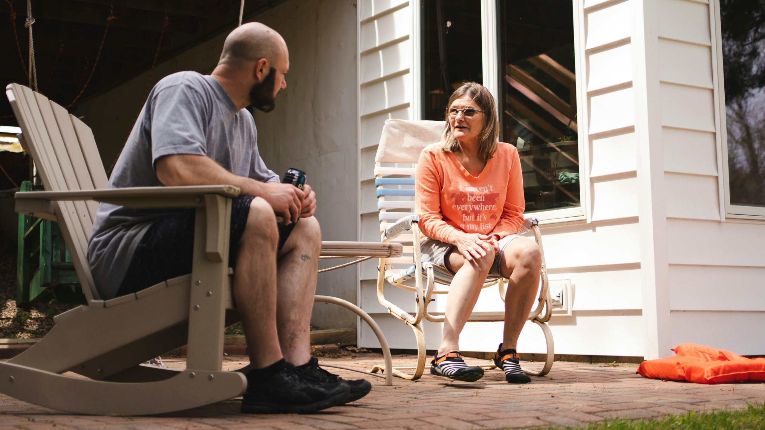 a man and a woman sitting on chairs outside of a house