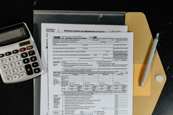 Calculator and tax forms on a dark surface.
