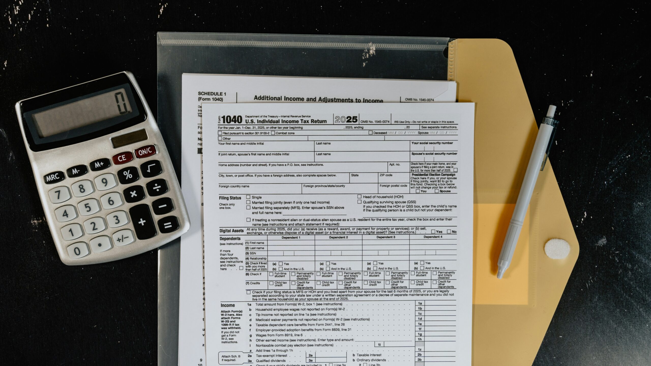 Calculator and tax forms on a dark surface.