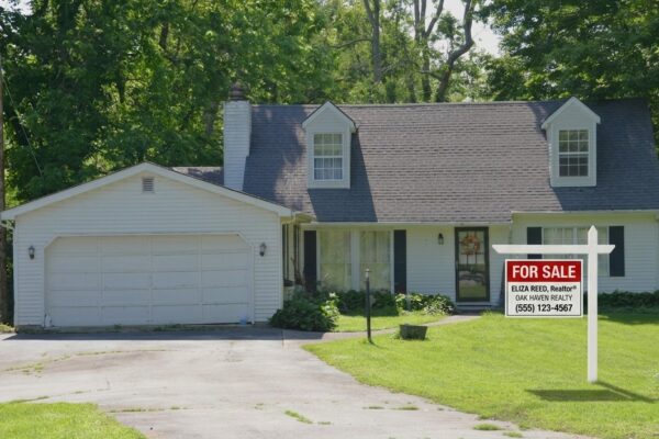 A white house with a garage, driveway, and green lawn.