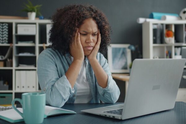 Young woman focused on remote work at home office desk with laptop.