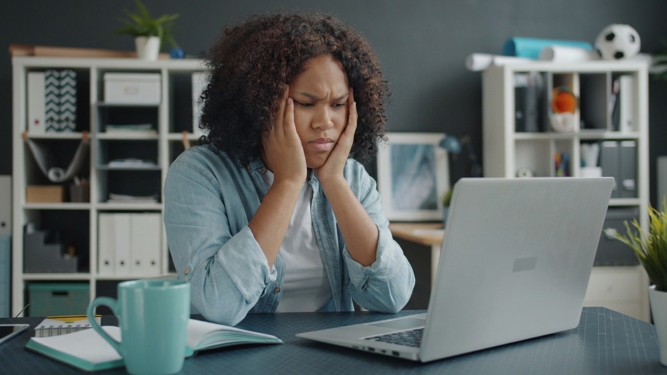 Young woman focused on remote work at home office desk with laptop.