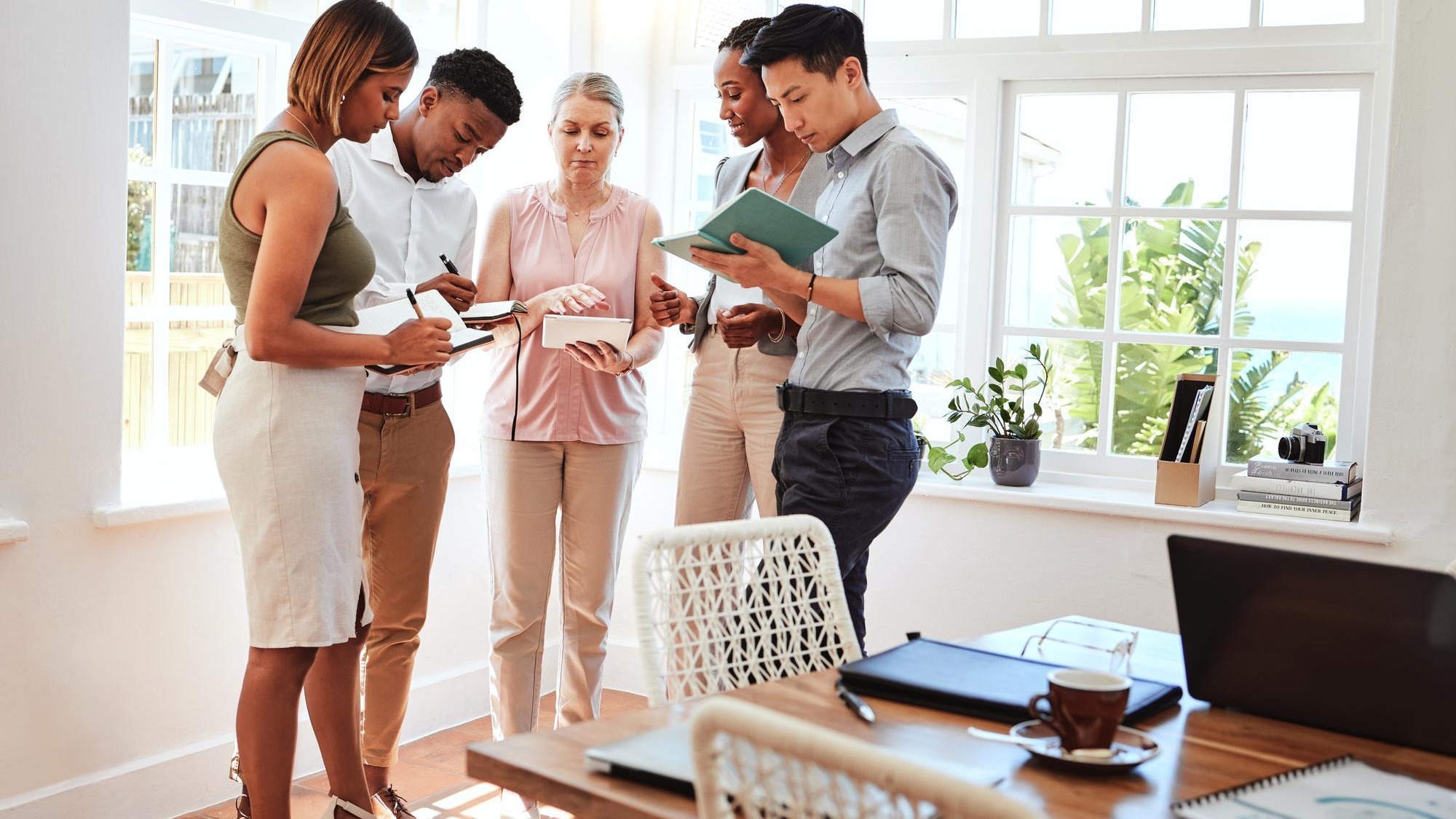 Business coach startup team workshop and mature business woman coaching men and women in modern office Diversity teamwork and writing note on strategy and planning advice from mentor or consultant