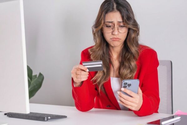 Business woman holding credit card and mobile phone Making payment sitting desk at office