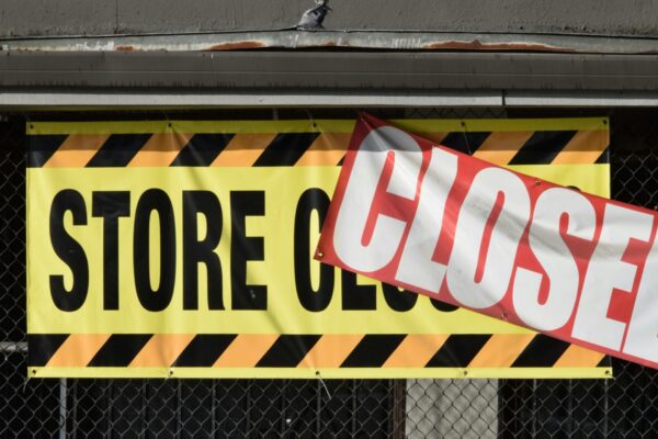 A store closed sign hanging from the side of a building