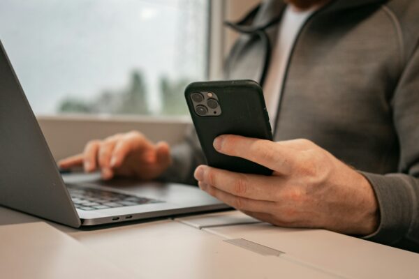 a man sitting in front of a laptop computer holding a cell phone