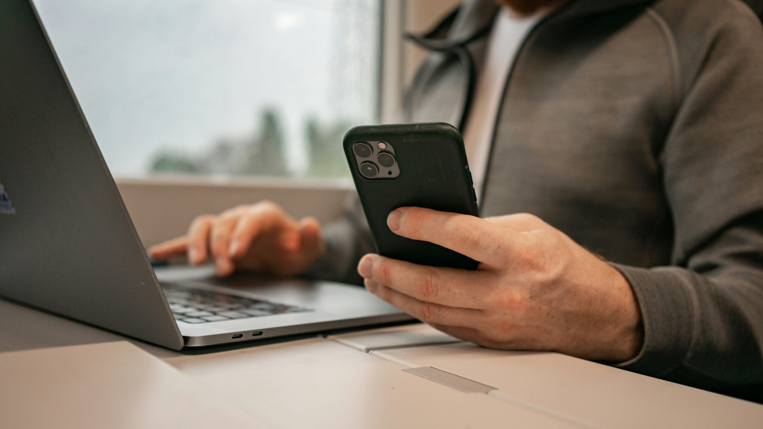 a man sitting in front of a laptop computer holding a cell phone