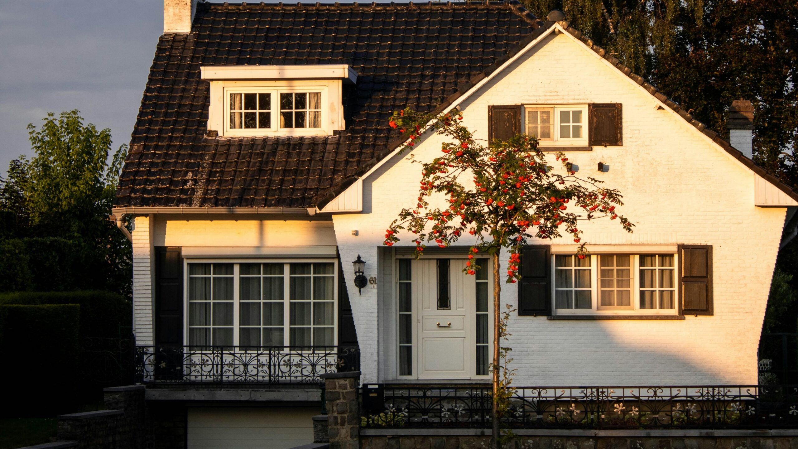 white and brown concrete house near green trees under blue sky during daytime