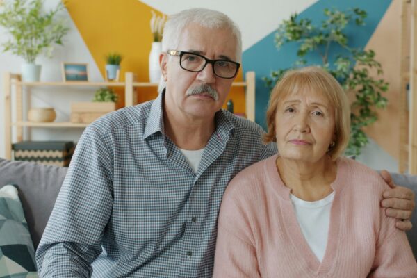 Elderly couple sitting on a couch indoors.