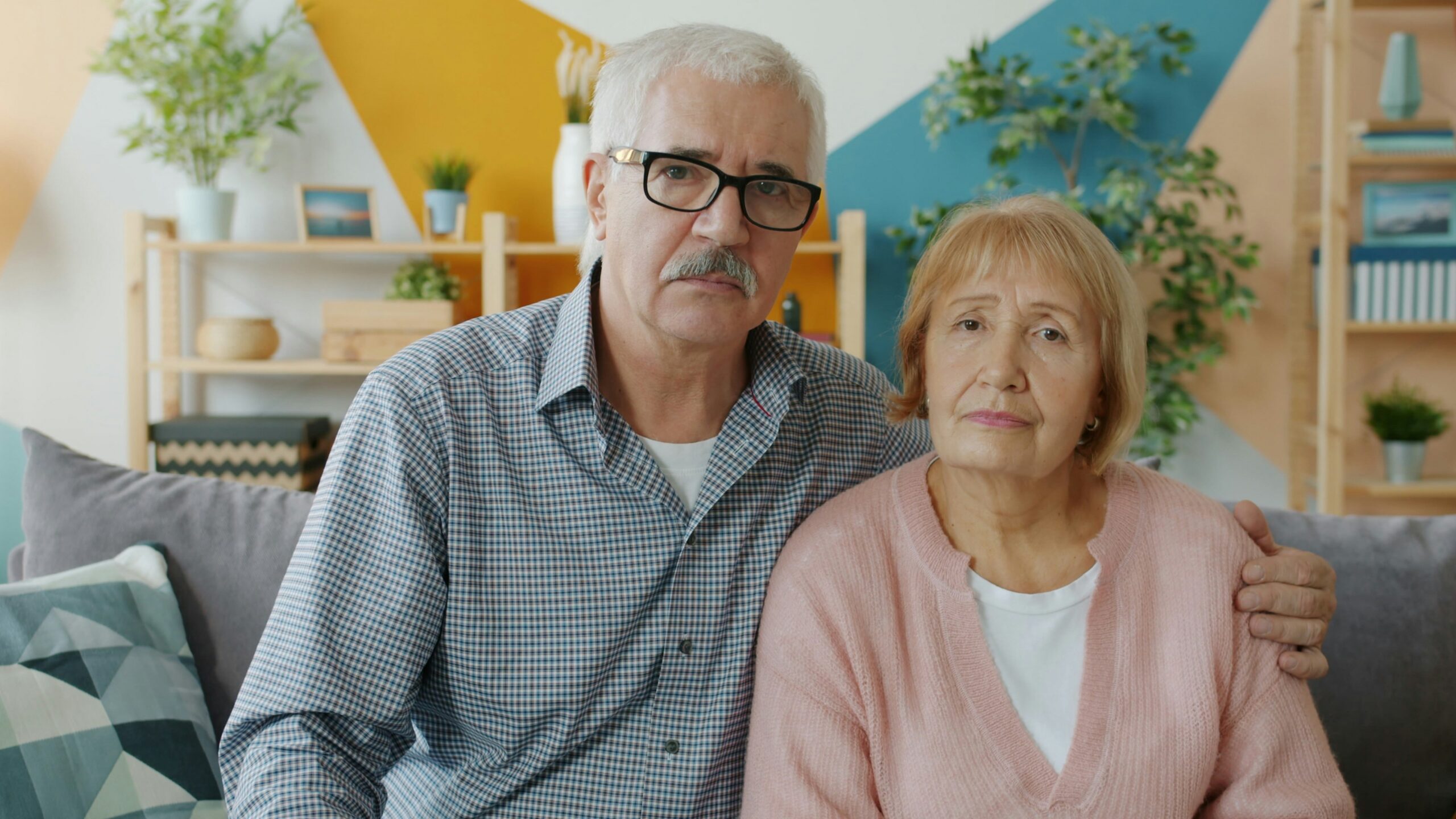 Elderly couple sitting on a couch indoors.