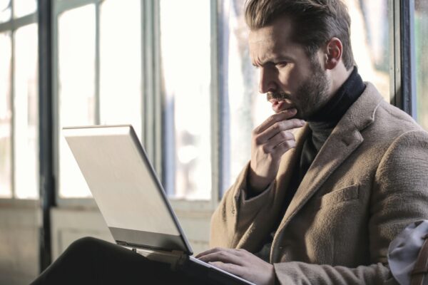 man holding his chin facing laptop computer