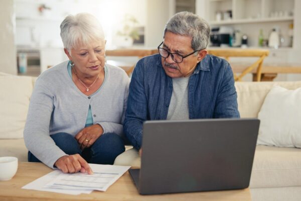 Elderly couple and laptop with document for financial planning investment or paperwork for retirement Senior man woman and tech with budget for online banking account or savings in home