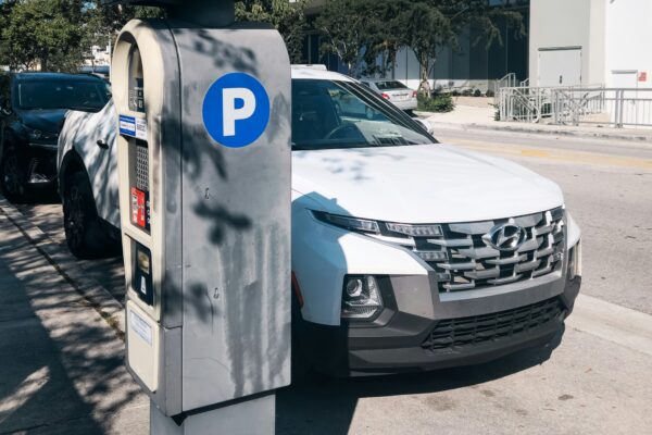 A white car parked next to a parking meter