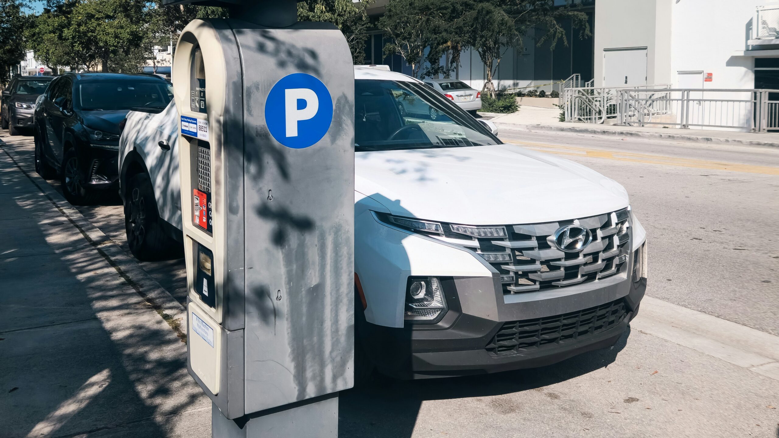 A white car parked next to a parking meter