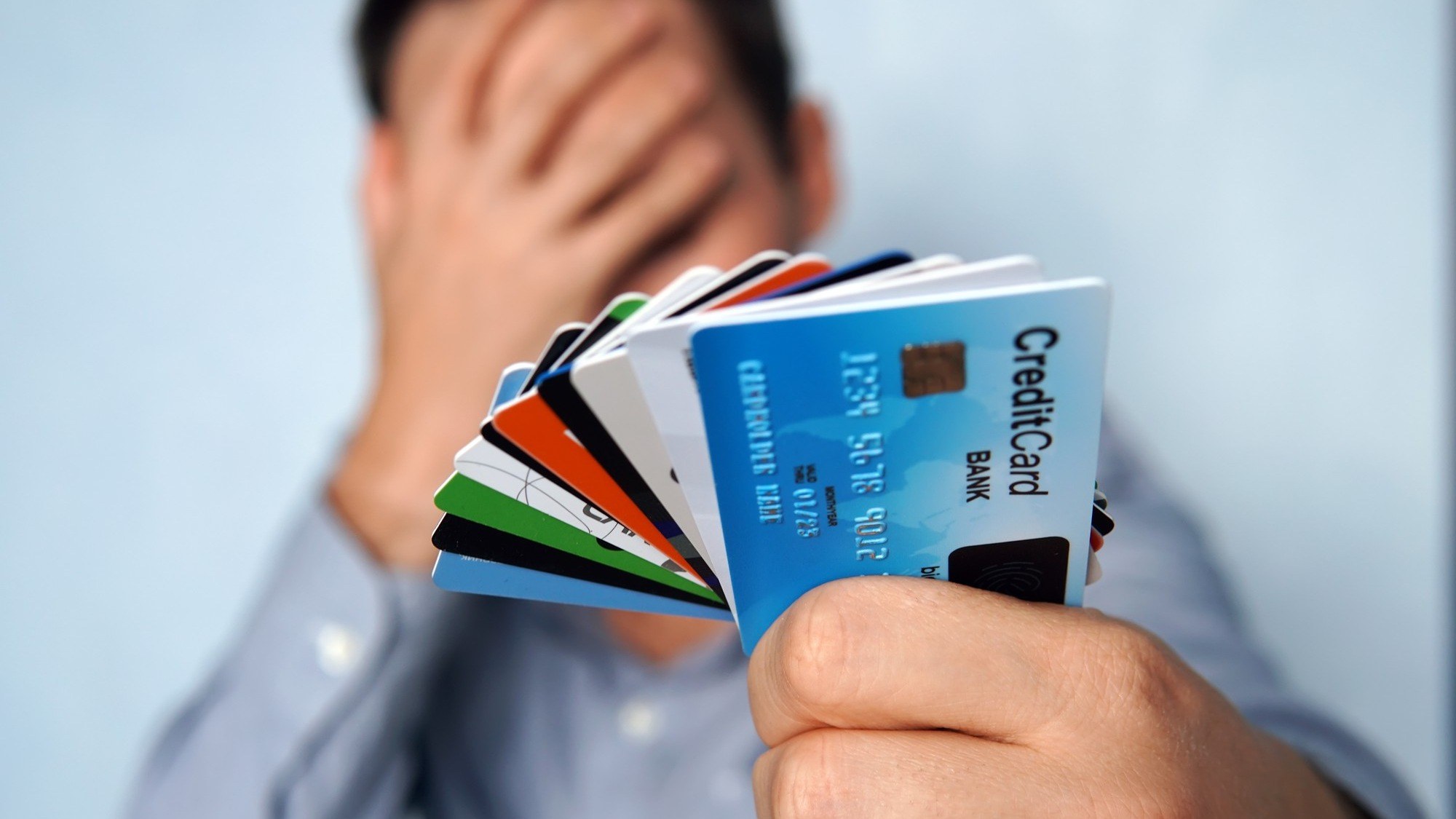 Image Credit: Confused man looking at many credit cards uncertain which/