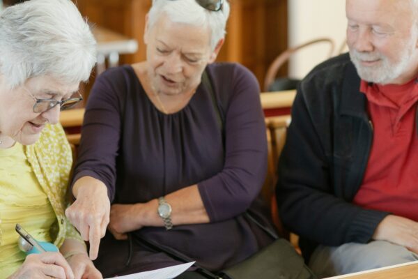 Three older adults are looking at a paper.