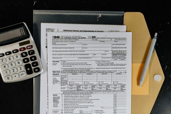Calculator and tax forms on a dark surface.