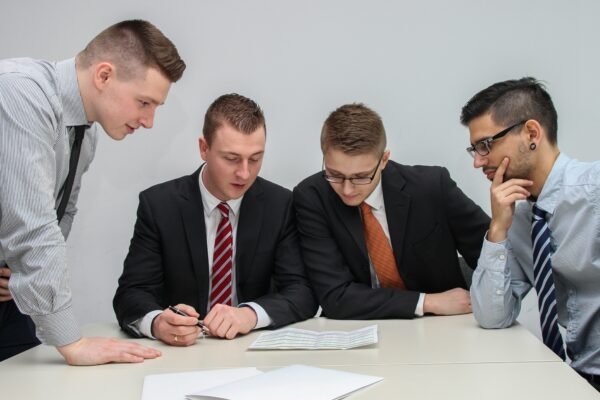 four men looking to the paper on table