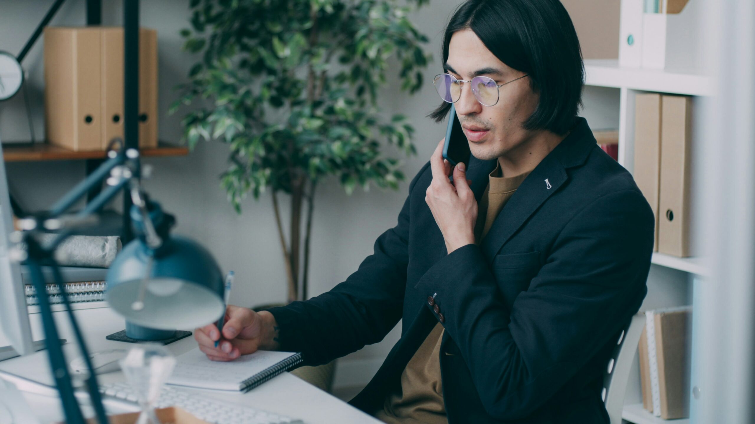 A man sitting at a desk talking on a cell phone