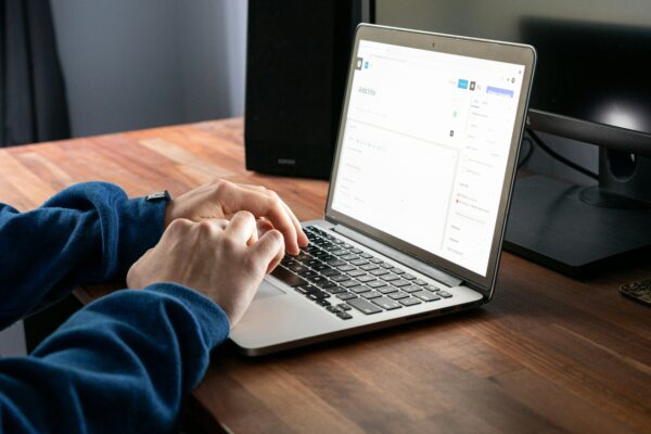 person using macbook pro on brown wooden table