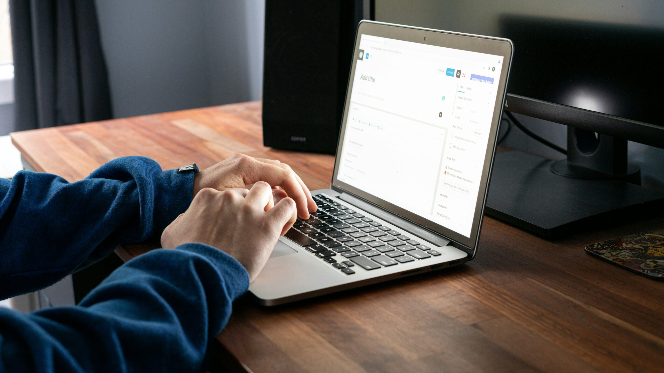person using macbook pro on brown wooden table