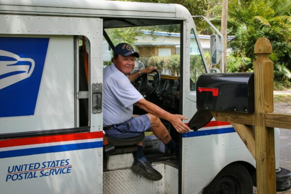 man in blue dress shirt sitting on white and blue bus during daytime