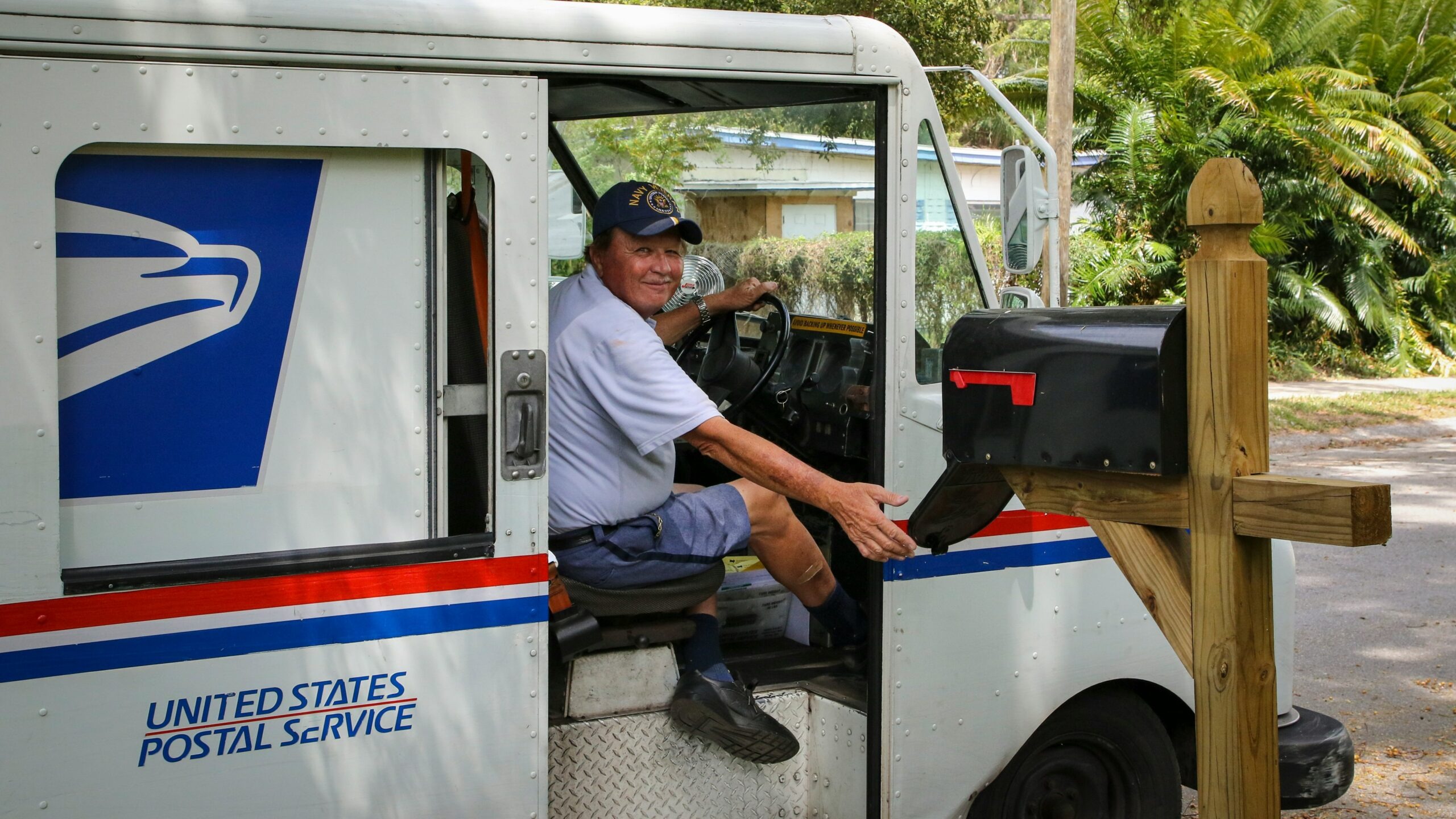 man in blue dress shirt sitting on white and blue bus during daytime
