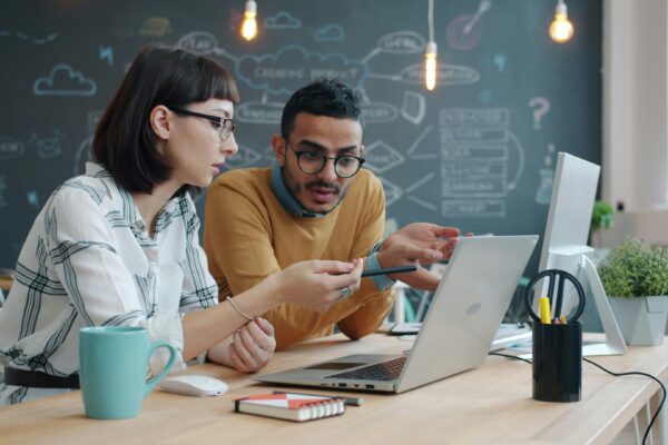 Two colleagues collaborating on a laptop at a desk