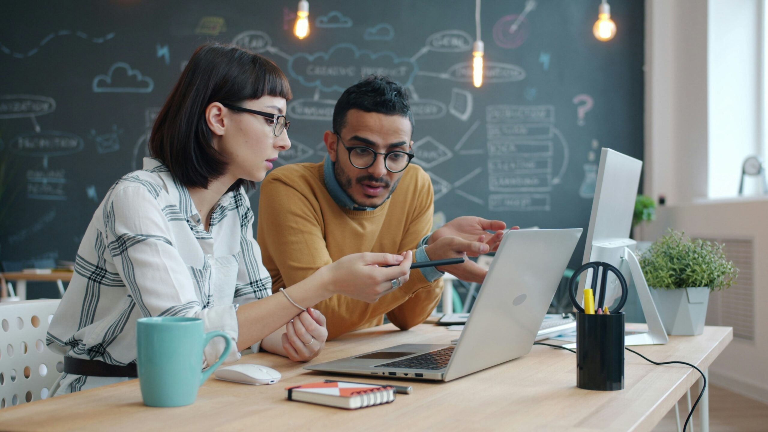 Two colleagues collaborating on a laptop at a desk