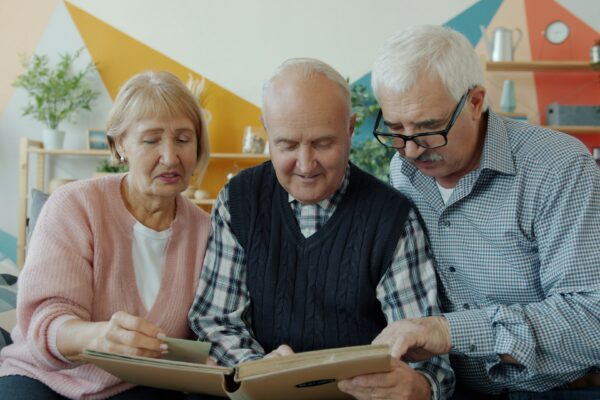 Three seniors looking at a photo album together