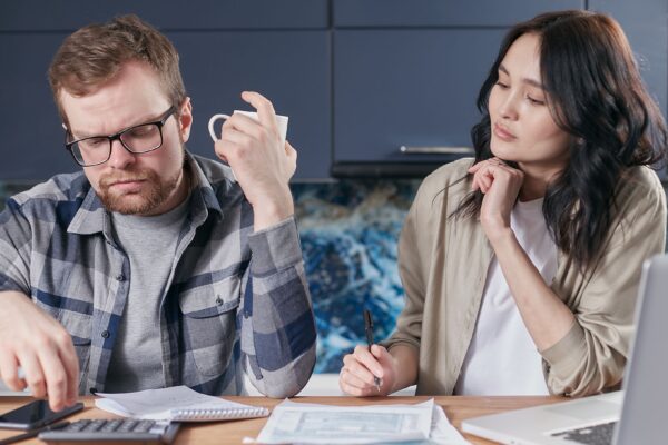 A focused young couple reviewing documents and managing their budget at home, showcasing modern financial challenges.