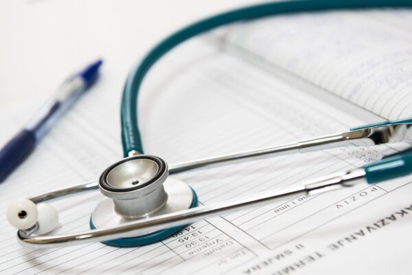 A stethoscope and pen resting on a medical report in a healthcare setting.