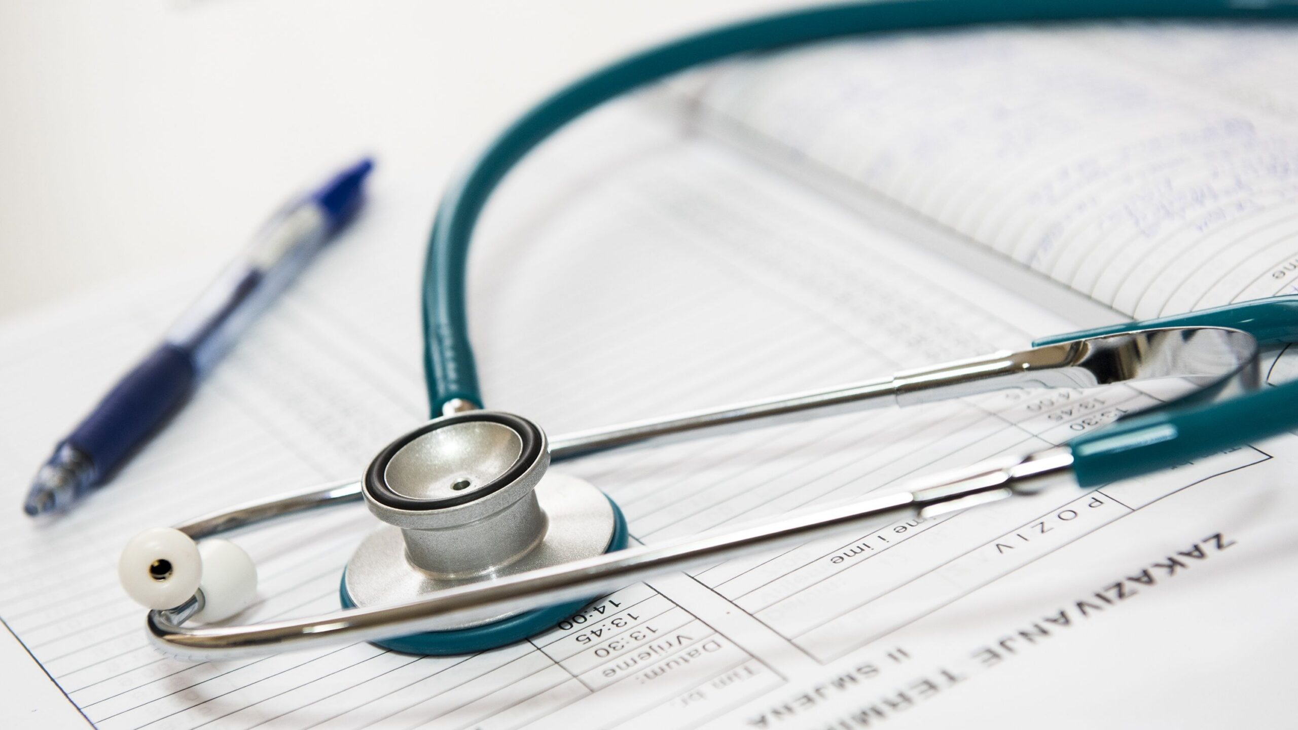 A stethoscope and pen resting on a medical report in a healthcare setting.