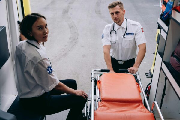 Two paramedics prepare a stretcher inside an ambulance, ready for an emergency response.
