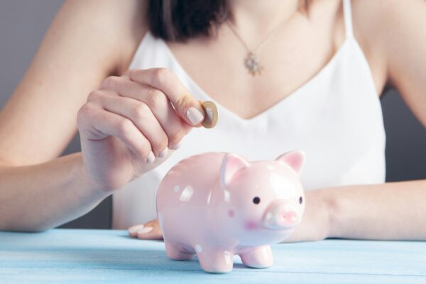 woman in white tank top holding pink pig figurine
