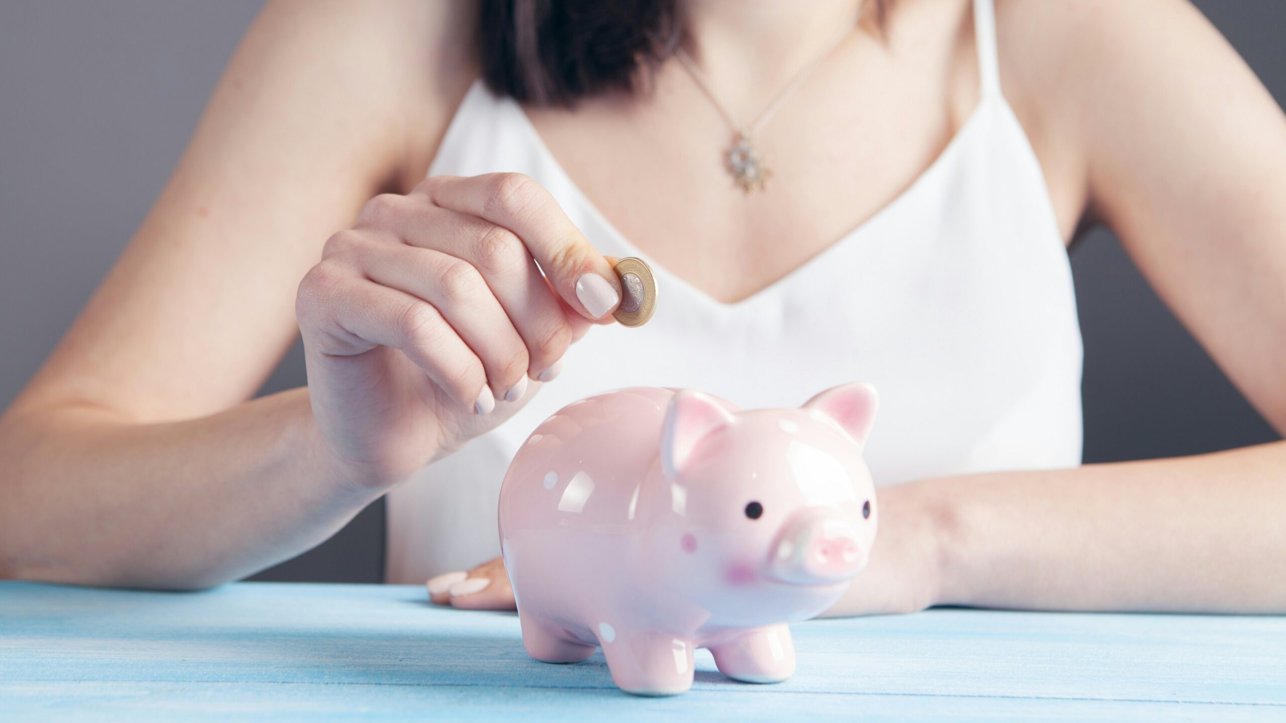 woman in white tank top holding pink pig figurine