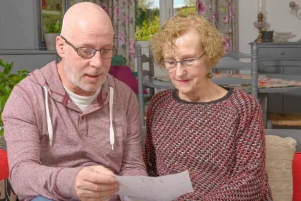 Mature man with woman holding paper on sofa at home