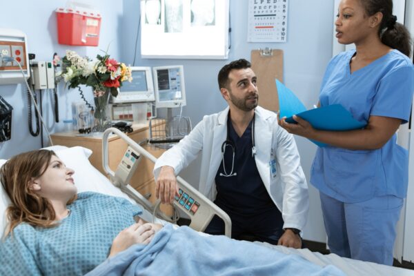 Doctors and nurse discussing patient's treatment in a hospital room.
