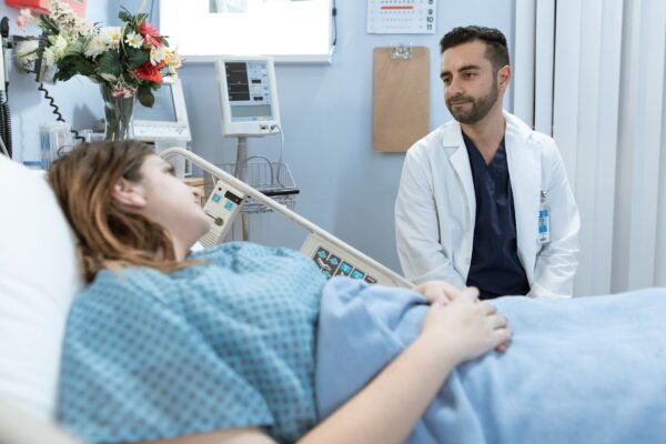 A doctor comforts a patient in a hospital room, emphasizing professional care.