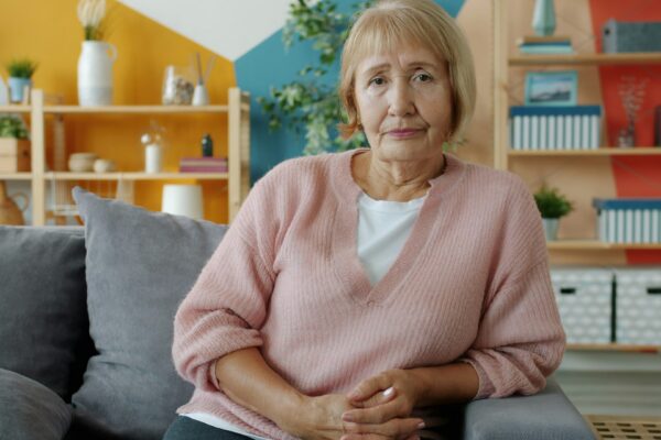 Elderly woman sitting on a couch in a living room.