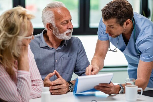 Serious doctor discussing with senior couple about their medical documents during appointment at clinic