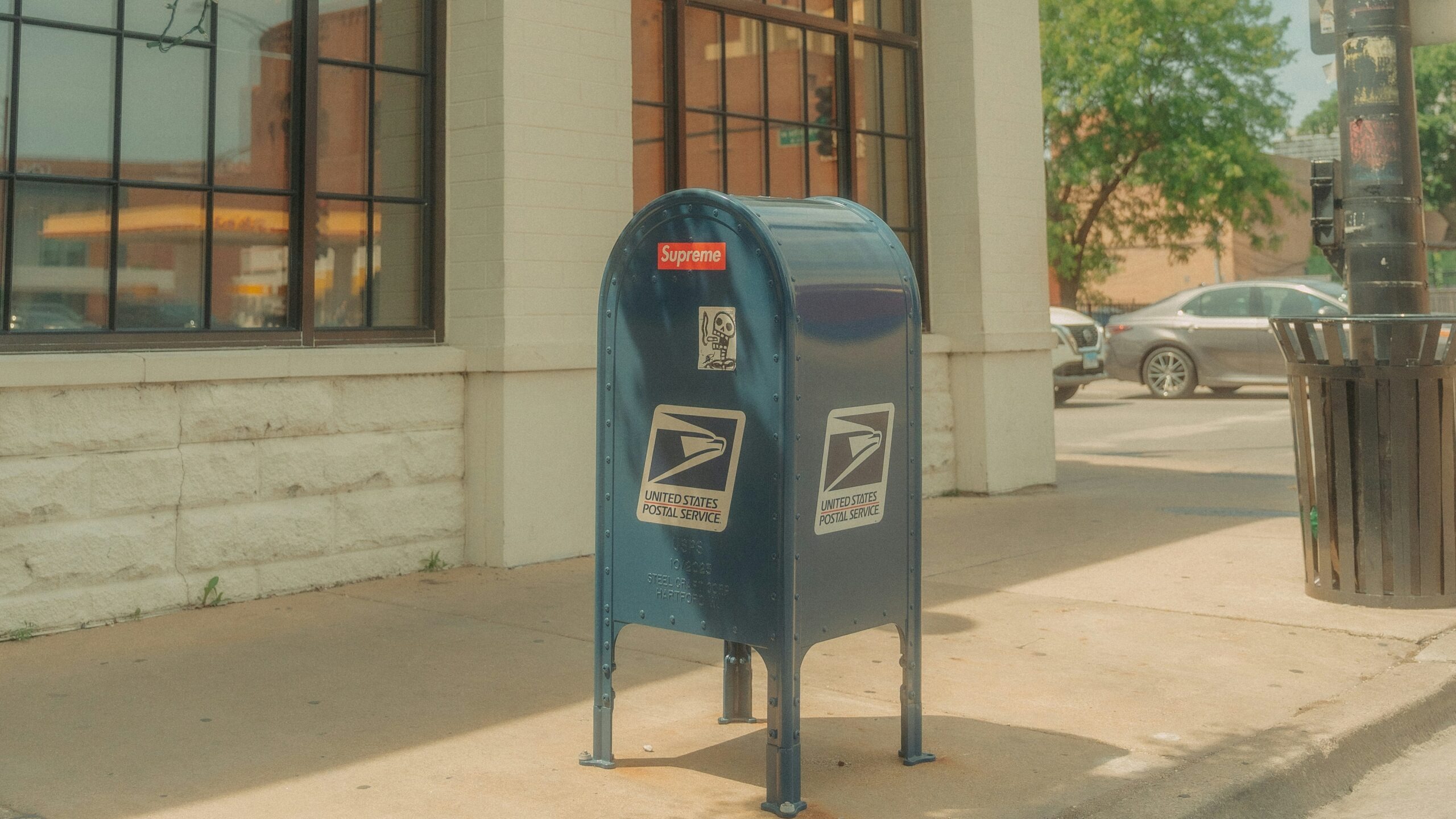 A blue mailbox sitting on the side of a street