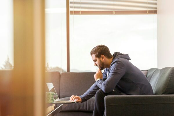 man sitting on sofa facing laptop computer