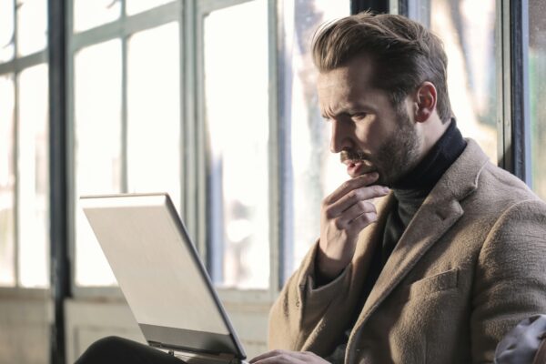 man holding his chin facing laptop computer