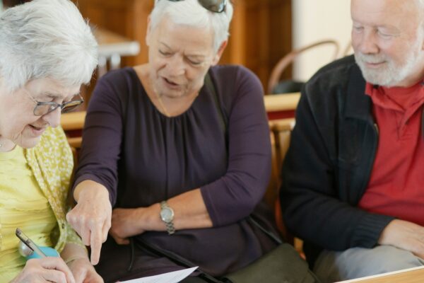 Three older adults are looking at a paper.